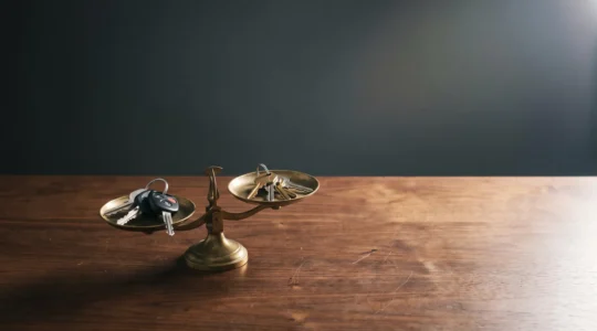 Clés de voiture et clés de maison posées en équilibre sur une balance symbolisant le risque financier du défaut d'assurance
